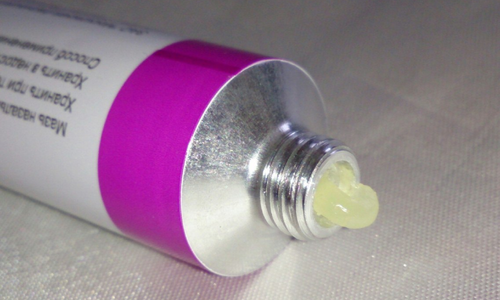 Mujer mayor en su baño sosteniendo un frasco de crema y sonriendo con tranquilidad